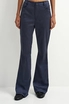 A person wearing dark navy wide-leg pants with black shoes, shown from the waist down against a plain light gray studio background.
