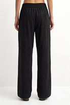 Black wide-leg trousers with an elastic waistband and a side pocket, shown from the back on a model against a white studio background.