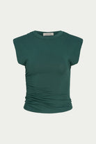 A dark green ribbed knit top with a crew neck and cap sleeves, featuring ruched detailing on the sides, shown against a light gray background.