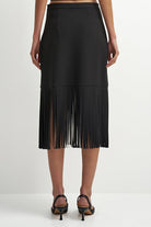 A black midi skirt with a fringe hem, shown on a model from the back against a plain white studio background.