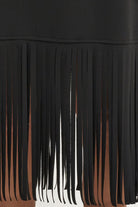 Close-up of a black fringe garment, showing long hanging fabric strips against a white background.